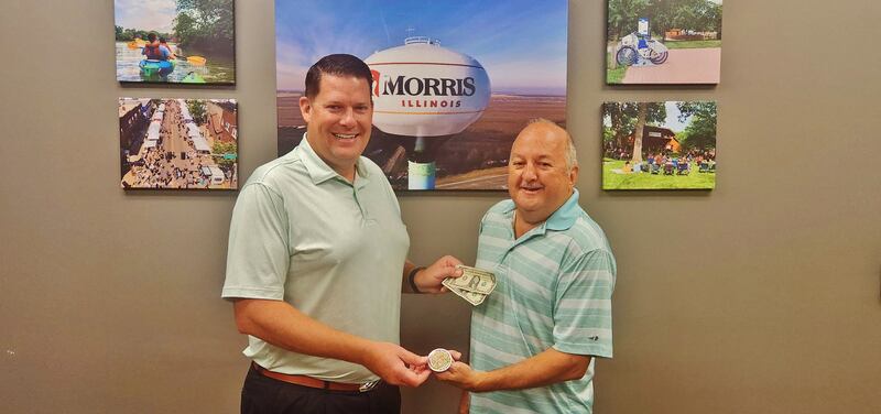 Morris Mayor Chris Brown purchases the first Grundy County Corn Festival button of the season from board vice president Jim Maskel.
