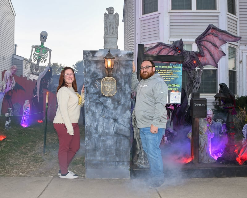 Phil, right, and his wife Dannielle Dienoff pose for a photo in front if a pillar that Phil made and are on display on Wednesday Oct. 16, 2024, that sits outside his home in Oswego that is part of his haunted yard trail.