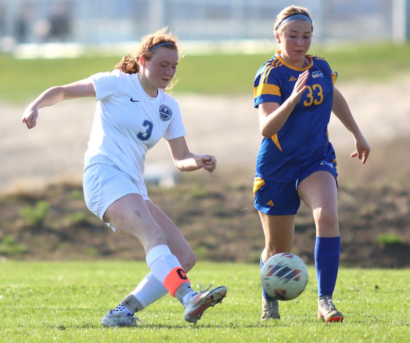 Woodstock’s Keira Bogott, left, scores the Blue Streaks’ second goal as Johnsburg’s Gabriella Kay defends in varsity soccer on Wednesday, April 23, 2025, at Johnsburg High School in Johnsburg.