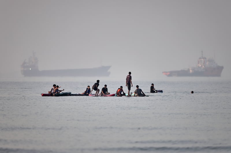 People gather on paddleboards in shallow water as cargo and service vessels are anchored in the Strait of Hormuz off Bandar Abbas, Iran, Monday, June 1, 2026. (Amirhosein Khorgooi/ISNA via AP)