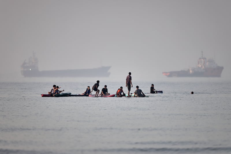 People gather on paddleboards in shallow water as cargo and service vessels are anchored in the Strait of Hormuz off Bandar Abbas, Iran, Monday, June 1, 2026. (Amirhosein Khorgooi/ISNA via AP)