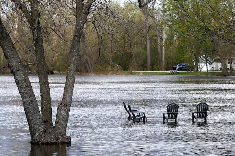 Four partially submerged chairs along South Wright Road near Burton’s Bridge on Sunday, April 19, 2026, as the Fox River continues to rise.