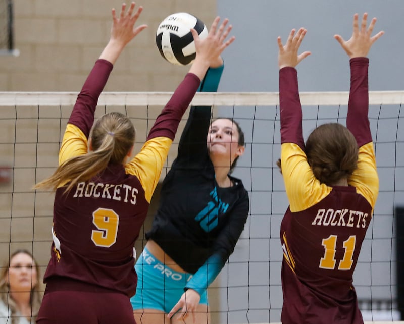 Woodstock North's Ava Kardaras (center) hits the ball between Richmond-Burton's Reagan Wisniewski (left) and Mia Furlan (right) during a Kishwaukee River Conference volleyball match on Monday, Sept. 15, 2025, at the Woodstock North High School.