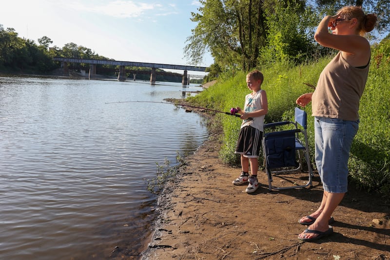 Kolton Baker, 7, of Bourbonnais, reels in his line at Fisherman Park in Kankakee on Saturday, June 28, 2025, as he participates in the NIAA Kankakee River Fishing Derby with his mother, Chris Gankel, right, for the third year. Baker, who learned to fish through the Kankakee County State's Attorney's Office's Reel Justice Fishing Club, said he hopes to make the Big Board this year.