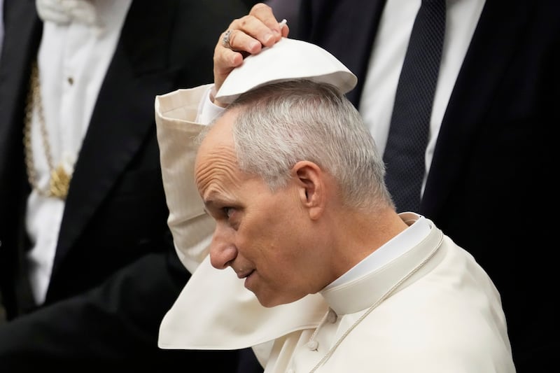 Pope Leo XIV tries a skull cap which was hand to him by faithful during the weekly general audience at the Vatican, Wednesday, Aug. 27, 2025. (AP Photo/Gregorio Borgia)