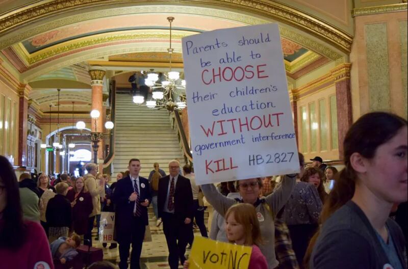 A woman holds a sign in the Statehouse on Wednesday, March 19, 2025, to oppose a bill relating to homeschooling.