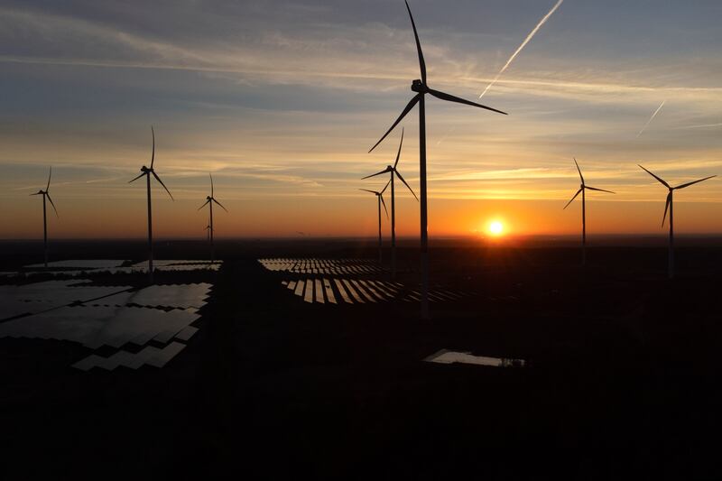 FILE - Wind turbines operate as the sun rises at the Klettwitz Nord solar energy park near Klettwitz, Germany, Oct. 16, 2024. (AP Photo/Matthias Schrader, File)