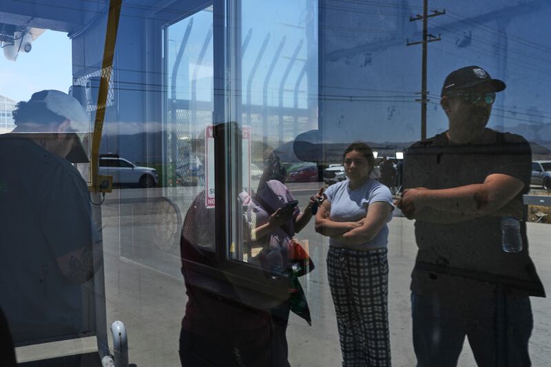 FILE - People wait outside of Glass House Farms, a day after an immigration raid on the facility, Friday, July 11, 2025, in Camarillo, Calif. (AP Photo/Jae C. Hong, File)