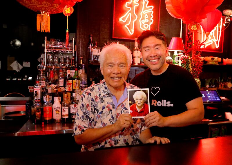 Perry Moy and his son, Jason, hold a photo of Perry's mother. Connie, inside the Plum Garden restaurant on Wednesday, July 2, 2025, in McHenry. The oldest single-family run restaurant in McHenry is celebrating its 60th anniversary.