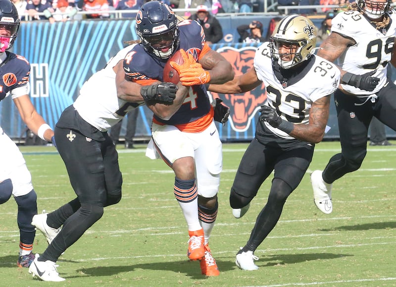 Chicago Bears running back D'Andre Swift carries the ball as he is brought down by New Orleans Saints safety Justin Reed and teammate safety Jonas Sanker on Sunday, Oct. 19, 2025 at Soldier Field in Chicago.