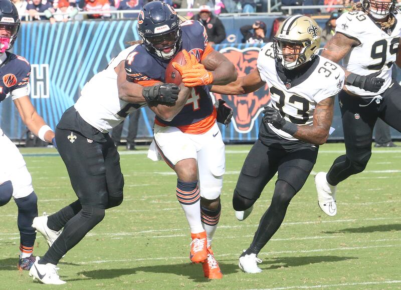 Chicago Bears running back D'Andre Swift carries the ball as he is brought down by New Orleans Saints safety Justin Reed and teammate safety Jonas Sanker on Sunday, Oct. 19, 2025 at Soldier Field in Chicago.