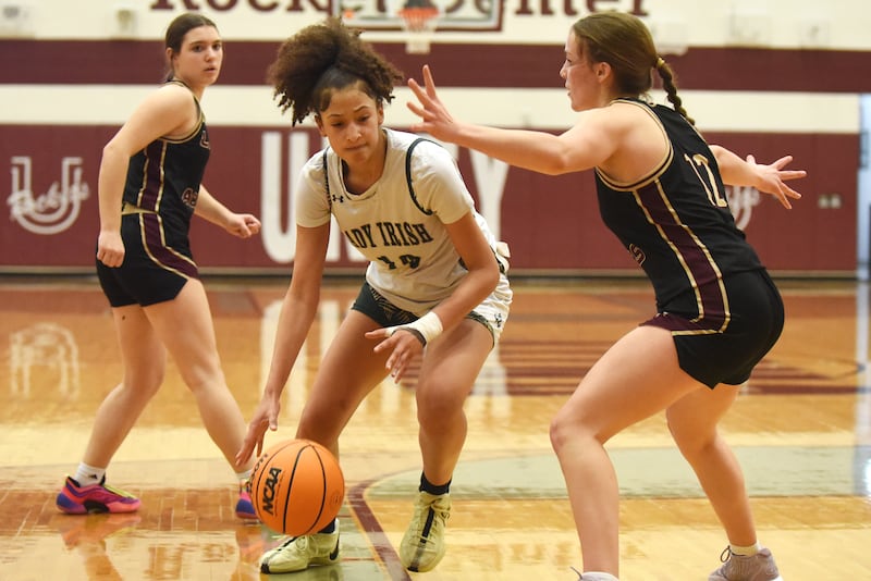 Bishop McNamara's Trinitee Thompson, center, looks to get past Mt. Carmel's Madeline Mann, right, during the IHSA Class 2A Tolono Unity Super-Sectional Monday, March 3, 2025.