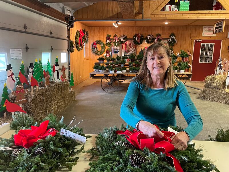 Wendy Richardson adjusts a ribbon on one of the fresh wreaths crafted on-site at the Richardson Christmas Tree Farm.
