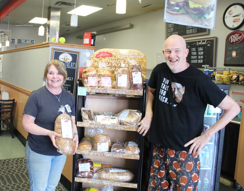 Breaking Bread owners Teri and Chris Plazak stand with their new Today's Temptations bread rack at the Cary location.