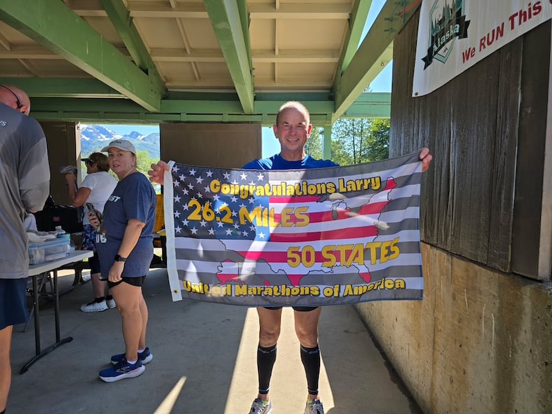 Larry Burton, 65, of Martinton, poses with a flag celebrating running a marathon in all 50 states. He completed the long journey on Aug. 6 by running a marathon in Juneau, Alaska.