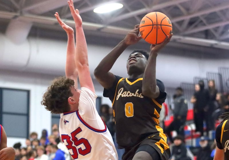Jacobs’ Samson Averehi, right, drives against Dundee-Crown’s Hudson Reardon in varsity boys basketball on Friday, Dec. 12, 2025, at Dundee-Crown High School in Carpentersville.