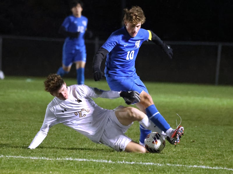 Sycamore's Conor Wickness slides to try and kick the ball away from Burlington Central’s Sam Knych Tuesday, Oct. 21, 2025, during their IHSA Class 2A regional semifinal match at Burlington Central High School.