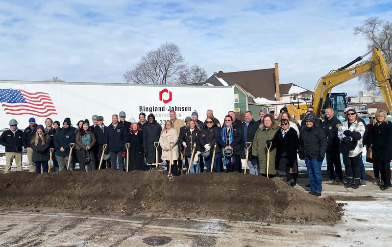 DeKalb area officials including elected leaders, staff and supporters of Safe Passage Inc., pose for a group photo on Friday, Dec. 5, 2025, at the agency's ceremonial groundbreaking to mark the start of construction on a new domestic violence survivor shelter at 217 Franklin St., in DeKalb.