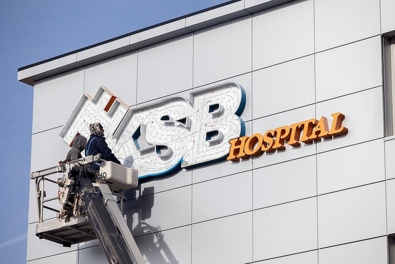 Alex Hartman (left) and Scott Coots work to remove the signage of the former KSB Hospital Friday, Dec. 13, 2024, in Dixon. Changing of the all the signs on the campus is expected to take a few months.