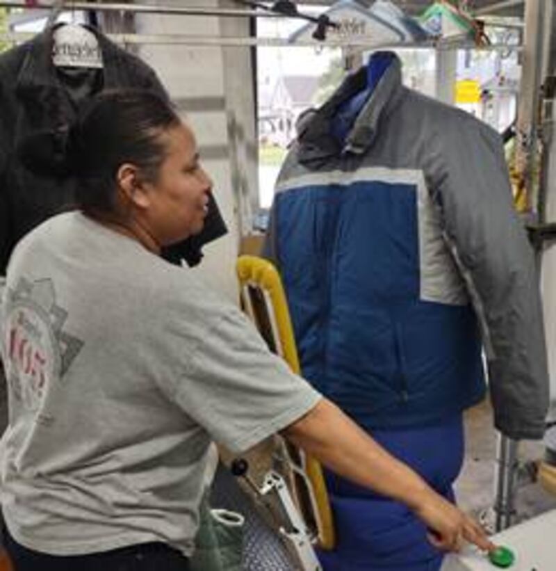 Candelaria Bello, lead pressor at Zengeler Cleaners, inspects one of this year’s donated coats.