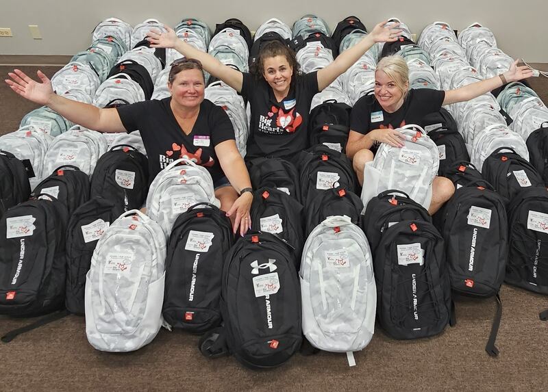 Big Hearts of Fox Valley President Jennifer Mobley (center), secretary Jill Caccia (left), and volunteer Melissa Weis pose with backpacks ready for donation during a packing event on Aug. 7, 2025.