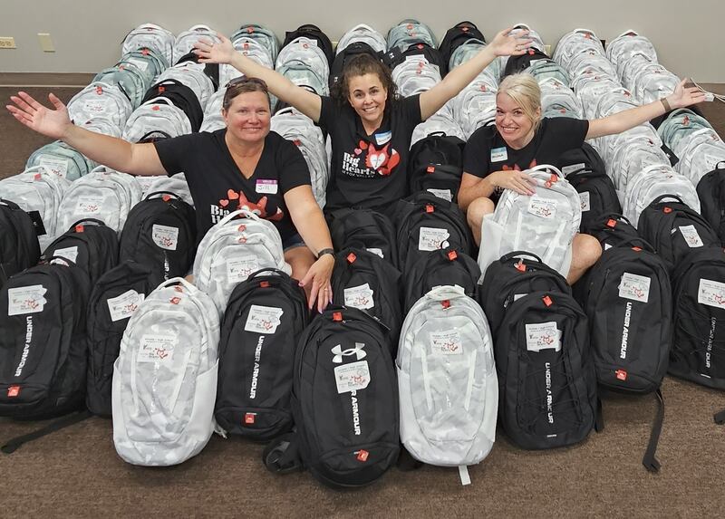 Big Hearts of Fox Valley President Jennifer Mobley (center), secretary Jill Caccia (left), and volunteer Melissa Weis pose with backpacks ready for donation during a packing event on Aug. 7, 2025.