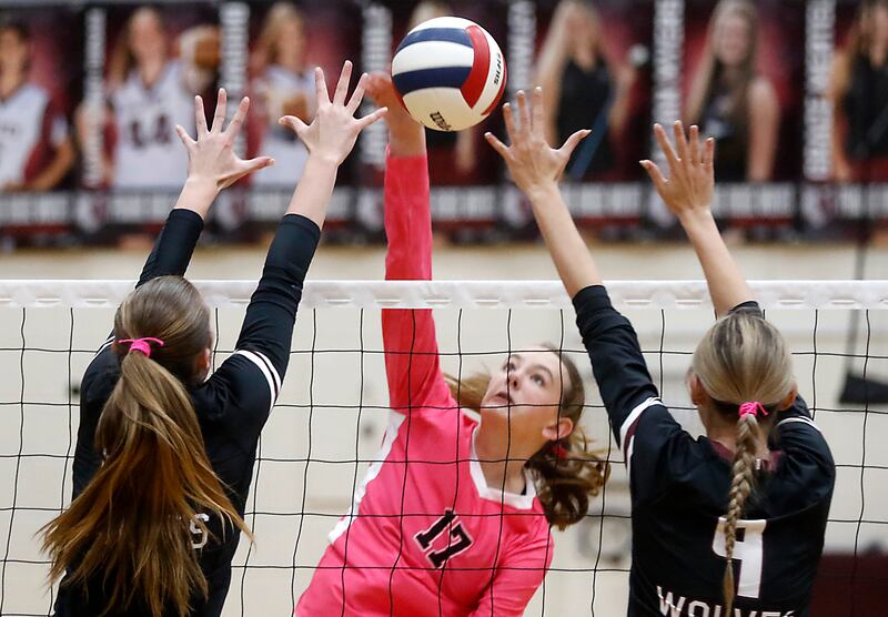 Huntley's Lucy Watson (center) hits the ball between the block of Prairie Ridge's Ella Glover-Taylor (left) and Prairie Ridge's Harleigh Serpico (right) during a Fox Valley Conference volleyball match on Tuesday, Oct. 14, 2025, at the Prairie Ridge High School in Crystal Lake.