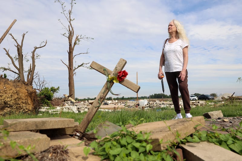 Sue Antonelli stands near the grave of a former pet cat on the property of her former Sandbar Road home in Aroma Township on May 19, 2026, which was leveled by the March 10 tornado while she was inside. Antonelli said she is still searching in hopes to find her two pet cats, Buddy and Scraps, that were in the home when the tornado struck.