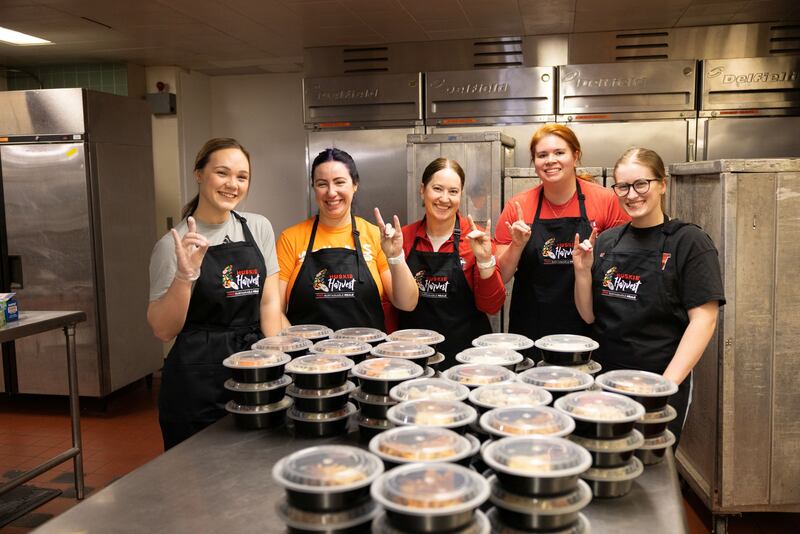 Student volunteers pose with leftover food made into ready-to-go frozen meals for students to enjoy for free through Northern Illinois University Huskie Harvest program. The initiative aims to reduce food waste and address food insecurity.