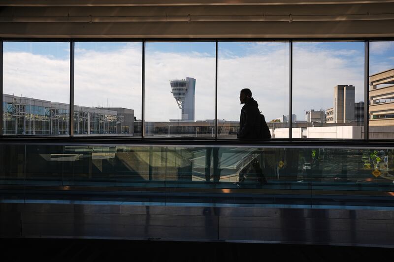 A traveler moves in view of a control tower at Philadelphia International Airport in Philadelphia, Wednesday, Nov. 5, 2025. (AP Photo/Matt Rourke)