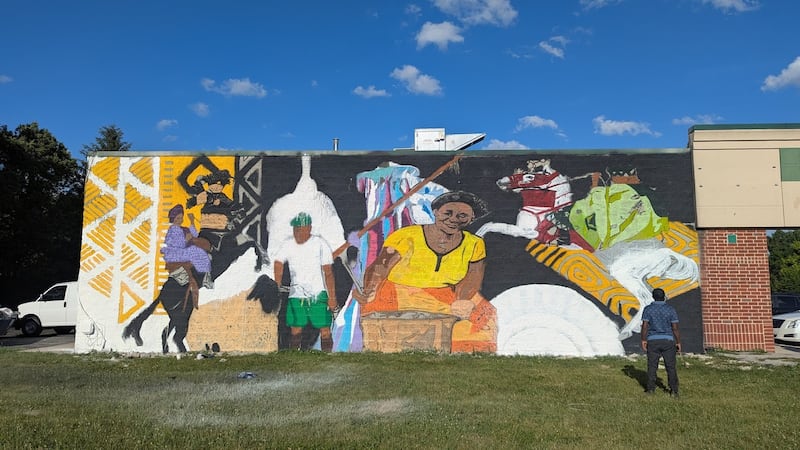 Uprizn Ikpemi, 40, of South Holland, a Nigerian-born American visual artist, muralist and art teacher, gazes on his mural on Monday, June 23, 2025, at 3109 Theodore St. in Joliet. The owner of the future O’Larry Asun Spot, a halal restaurant that will feature West African dishes, hired Ikpemi to paint the mural on the side of the restaurant.