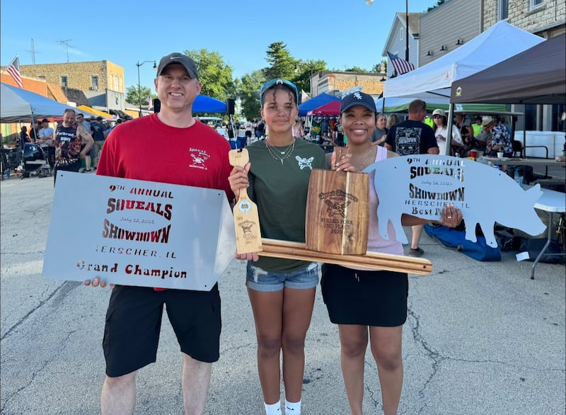 Herscher native Mike Janssen, left, holds the Squeals Showdown trophies with his daughter, Lexi, center, and wife, Kasha, that their team, Squealin' Alright, took home from the July 12 event.