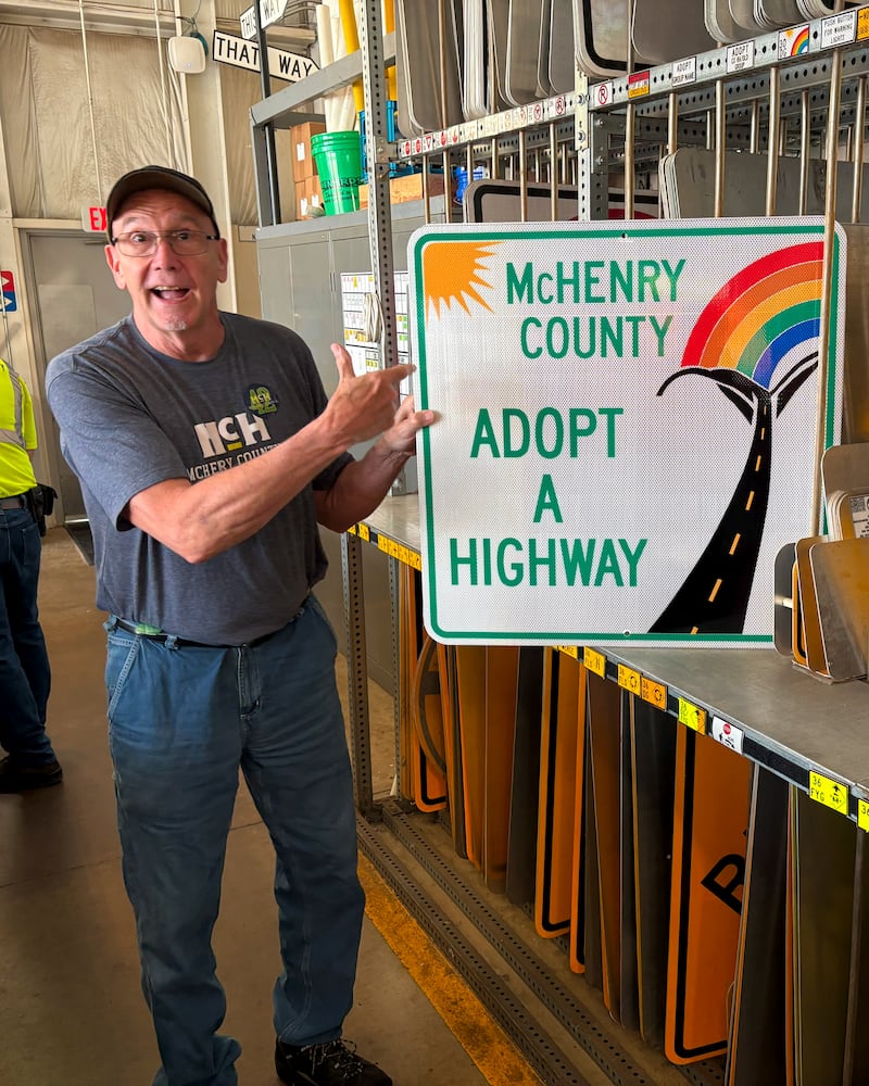 McHenry County sign shop supervisor Andrew Rose holds up an Adopt-a-Highway sign in June 2025. Rose designed the sign.