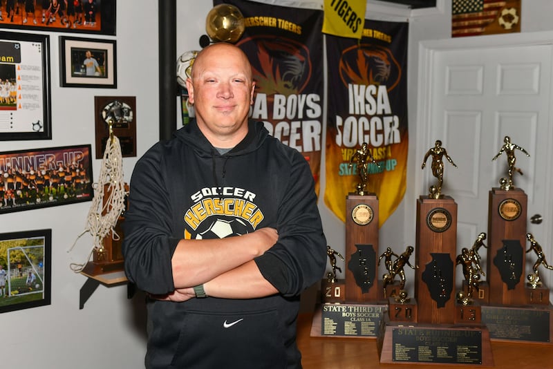 Herscher’s Alan High, head coach of the boys soccer team for 17 years, stands in his basement surrounded by the accolades from his coaching career. High tallied 306 victories, 11 IHSA Class 1A Regional titles, four sectional crowns and made two trips to state, placing second in 2013 and third in 2014.