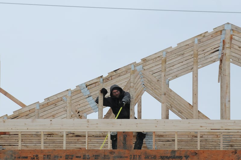 A construction worker takes a measurement on a home being built on Eagle Bluff Drive in Bourbonnais in January 2015.