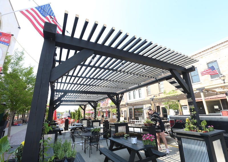 Kelsey Brannan of Country Kids Farm Market, arranges flowers in a pot on Thursday, May 8, 2025 along Mill Street downtown Utica. Utica businesses kicked off the outdoor dining season by setting up patio furniture, flowers, decorations and canopies. The outdoor dining season on Mill Street runs through October.