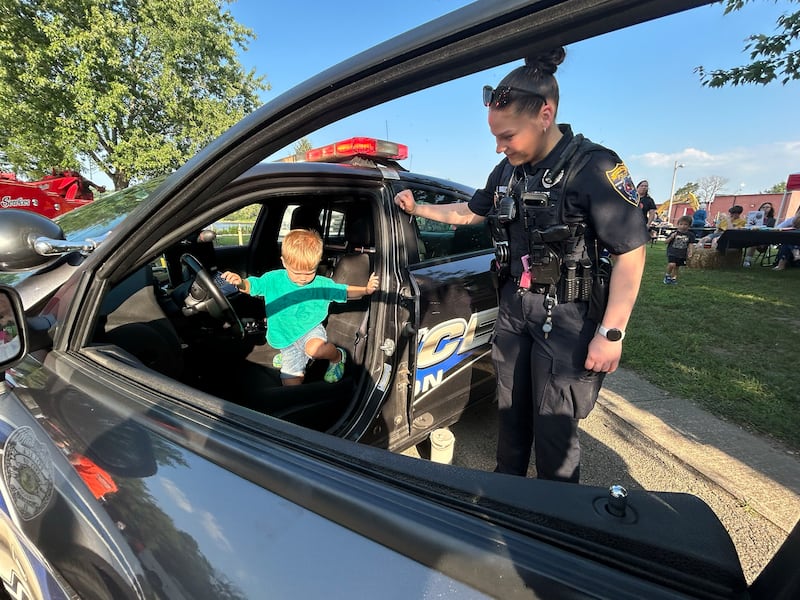 Oregon Patrol Officer Taylor Buckwalter helps Reed Wehmhoefer, 2, of Oregon, out of her squad car at the National Night Out event in Oregon on Tuesday, Aug. 5, 2025. The event was organized by the Oregon Police Department and included displays and trucks provided by the fire department and public works departments.