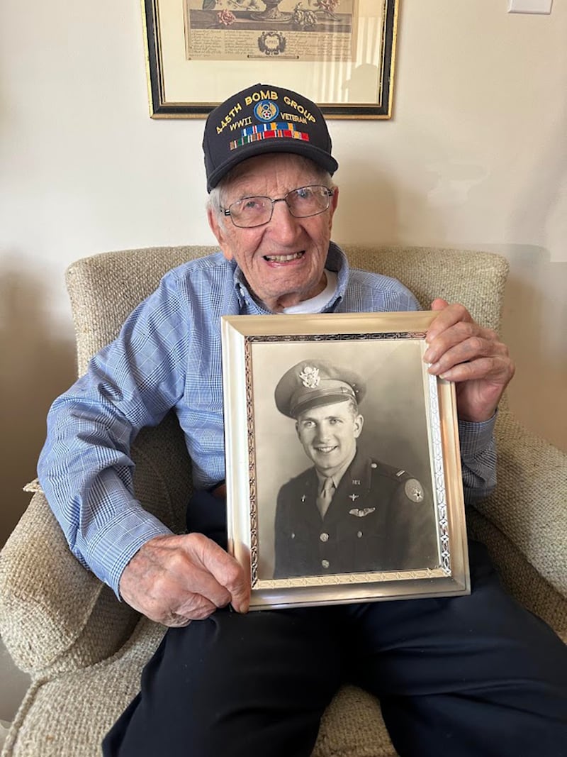 105-year-old Ed "Bud" Berthold holding a photo of himself from when he served in the Army Air Force during World War II from 1943 to 1945.