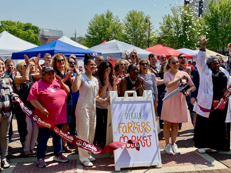 Business owners and members of the DeKalb Chamber of Commerce cheer as a ribbon is cut by the chamber's marketing and events manager Virginia Filicetti to celebrate the 30th year of the DeKalb farmers market on Thursday, June 5, 2025.