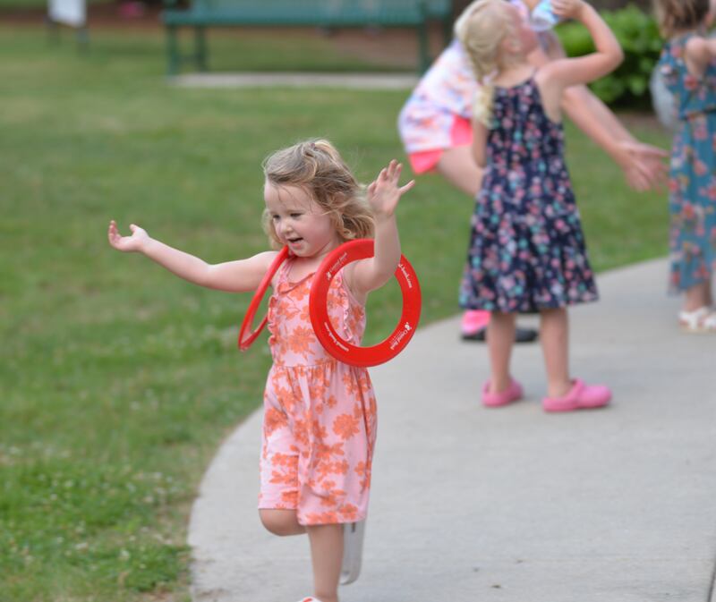 Evelyn Whalen, 3, of Oregon, plays with two plastic flying rings as she enjoys the music of “Buzzed by SonSET,” at the Oregon Park District’s Concert in the Park on Tuesday, June 24.