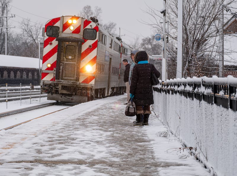 Commuters wait to board an approaching Metra train heading to Chicago at the College Avenue station in Wheaton on the morning of Tuesday, Jan. 9, 2024.