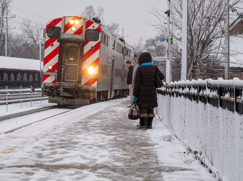 Commuters wait to board an approaching Metra train heading to Chicago at the College Avenue station in Wheaton on the morning of Tuesday, Jan. 9, 2024.