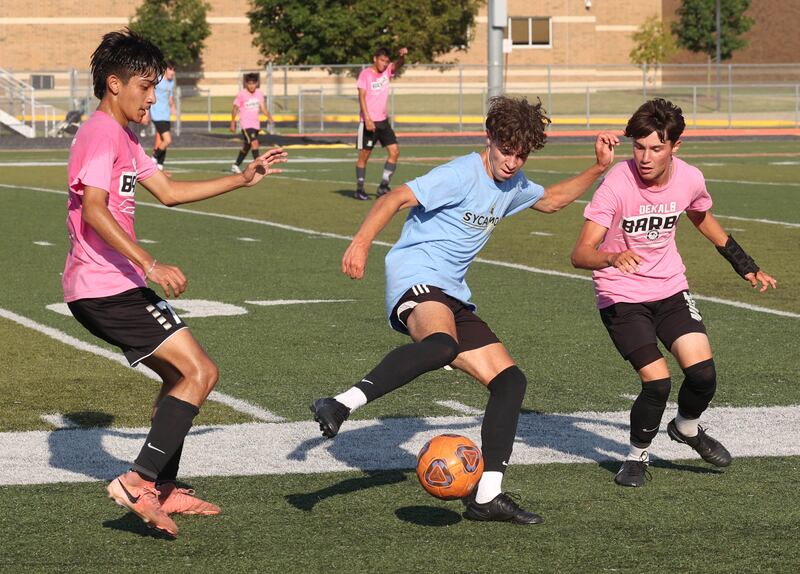 Sycamore’s Noah Daykin works between two DeKalb defenders Monday, July 14, 2025, during a summer boys soccer friendly at DeKalb High School.