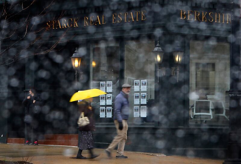 A yellow umbrella brightens up a rainy day as pedestrians walks around the Historic Woodstock Square on Friday, March 8, 2024. I love the splash of color that the yellow umbrella brings to the image,