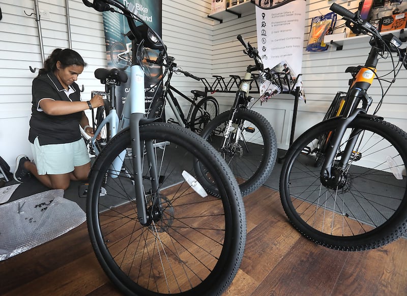 Josie Mathew installs a rack on electric bicycle on Friday, August. 15, 2025, at the Windy City Wheelers shop in the McHenry Riverwalk Shoppes.