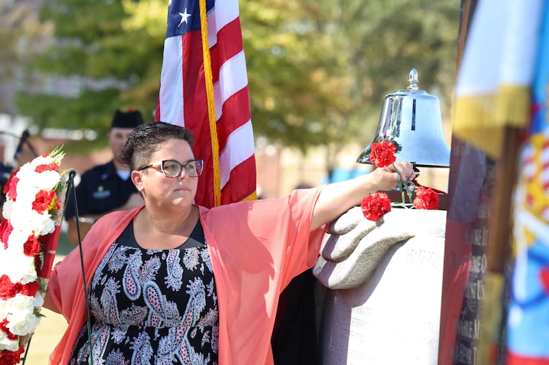 Danielle Dugan, administrative assistant with the Bradley Fire Department, places a flower upon the memorial wall as each of Kankakee County's eight fallen firefighter's names are read aloud during the 44th Kankakee County Fallen Firefighter Memorial Service on Friday, Oct. 3, 2025. Dugan helped revive the memorial event in 2017.