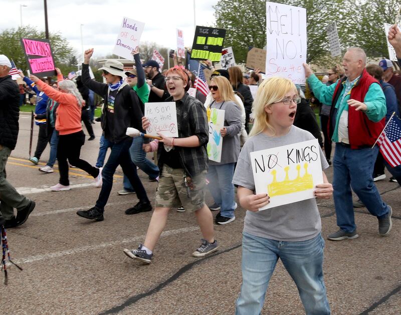 Protesters cross Sycamore Road at Barber Greene Road Saturday, April 19, 2025, during a “No Kings” rally and march in DeKalb. The group was protesting what they’ve argued is the unlawful and harmful federal policies of President Donald Trump and his administration.