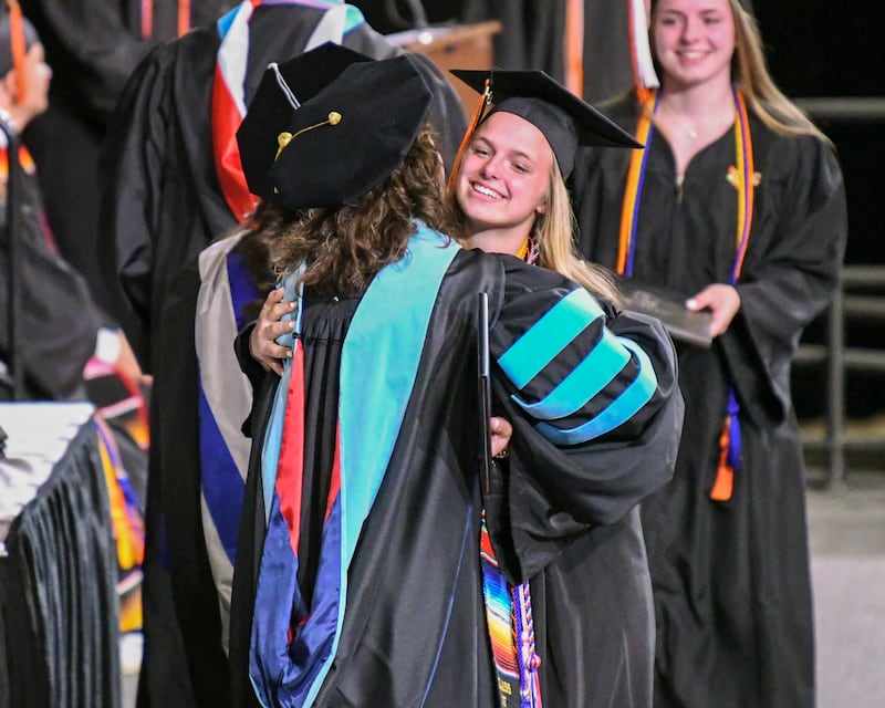 A DeKalb High School senior is all smiles and gets a hug as she receives her diploma on Saturday, May 24, 2025, during the Class of 2025 Commencement ceremony held at the NIU Convocation Center in DeKalb.