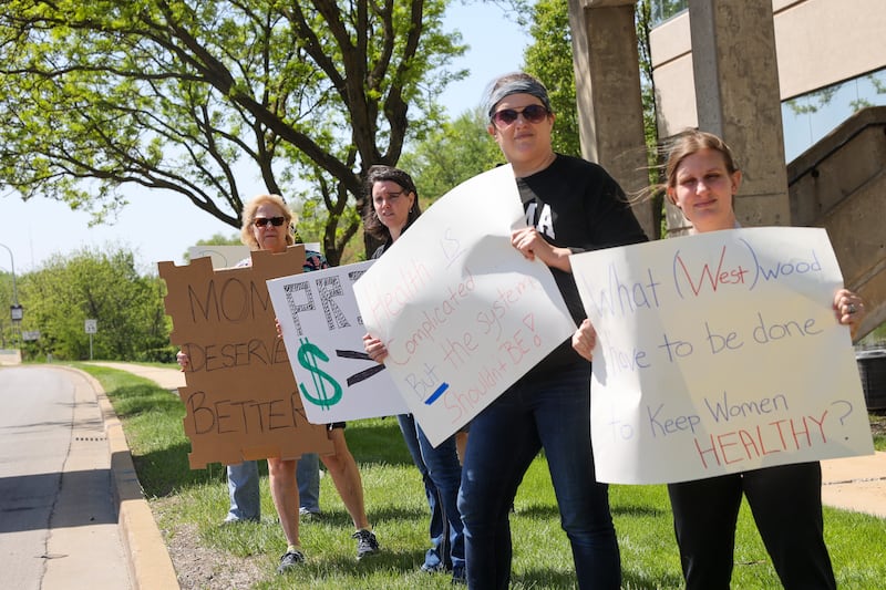 Several attendees hold signs opposing Prime Healthcare ending its contract with Westwood Obstetrics & Gynecology at Saint Mary's Hospital along West Court Street during a rally on Saturday, May 10, 2025. Dr. Valerie Goldfain, left, a longstanding doctor with Westwood, and Tali Gardner, of Kankakee, a 15-year labor and delivery nurse, second from left, joined local mothers and Westwood patients Katie Lisko, of Bradley, and Jessica Merrill, right, of Kankakee, for the rally.