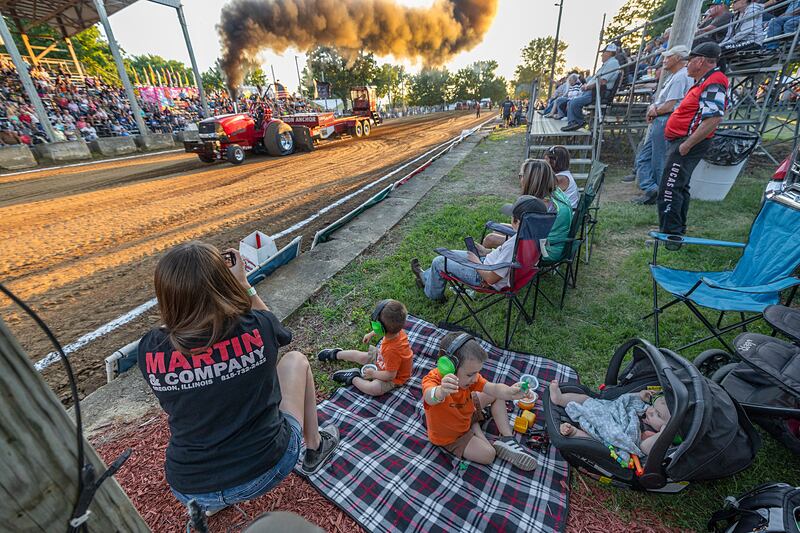 The Heeren family, Nikki, Hank, Hunter and Harvey, watch Jordan tear down the track in the Red Express on Wednesday, Aug. 7, 2024, at the Carroll County Fair’s tractor pull in Milledgeville.